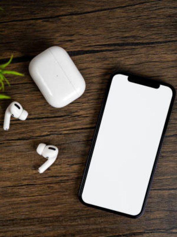 Smartphone with white on display, bluetooth headphones on wood table. Top view