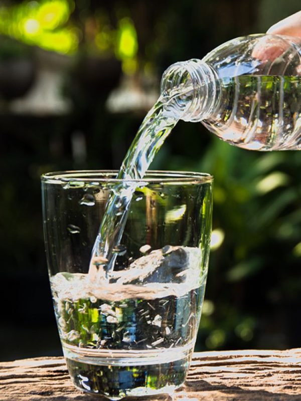 Female hand pouring water from bottle to glass