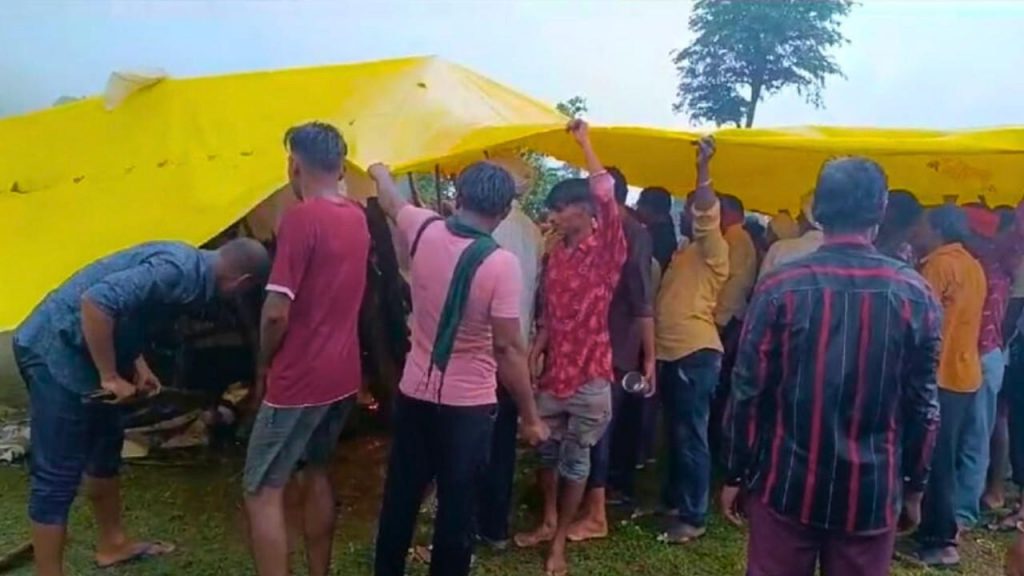 Villagers performing last rites by covering tarpaulin in rain